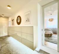 A hallway in a 3-room apartment with a tiled floor, decorative paintings, and a mirror.