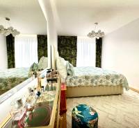 A bedroom in a three-room apartment with an elegant mirror and floral pattern.