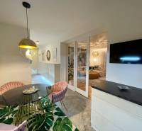 Dining area with a round table, pink chairs, and interesting lighting in a 3-room apartment.