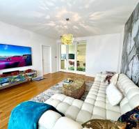 Living room in a three-room apartment with a stylish sofa and a television on the wall.