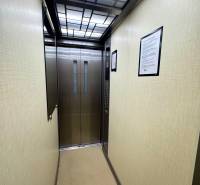 An elevator with an illuminated ceiling and stainless steel doors.