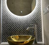 Round backlit mirror and gold sink in a 3-room apartment.