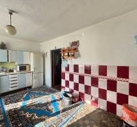 A kitchen in a family house with carpets, white cabinets, and red and white tiles.