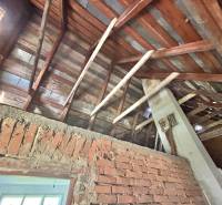 Attic in a family house with exposed roof structure and brick wall.