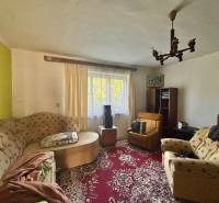 Living room in a family house with older furniture, carpet, chandeliers, and decorative elements.