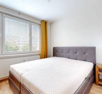 Bright bedroom in a 3-room apartment with a large window and simple furnishings.