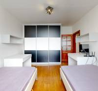 A bedroom with a built-in wardrobe, two desks, and two beds in a three-room apartment.