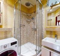 Bathroom with a glass shower enclosure, sink, and washing machine in a 3-room apartment.