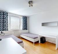 A bright room with a bed and a desk in a 3-room apartment with wooden flooring.