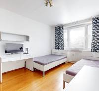 A room in a 3-room apartment with two beds, a table, and a television.