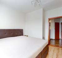 A bedroom with a brown bed and a white wall in a 3-room apartment.