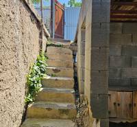 Stone steps leading up to the gate of the cottage in Čaňa surrounded by greenery.