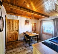 Wooden interior of a cabin with a dining table, chairs, and decorative lighting.