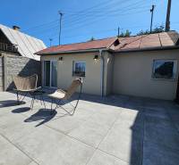 A cottage in Čaňa with a terrace, two chairs, and a table under the blue sky.