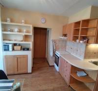 A kitchen in a 3-room apartment with wooden cabinets, appliances, and decorative shelves.