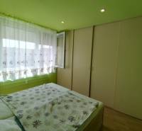 Bedroom in a 3-room apartment with built-in wardrobes and a large window with white curtains.