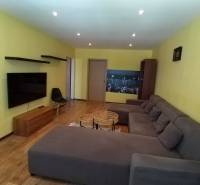 A living room in a three-room apartment with a comfortable sofa and a TV on the wall.