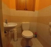 A toilet with a cabinet in a 3-room apartment, light tiles, yellow walls.
