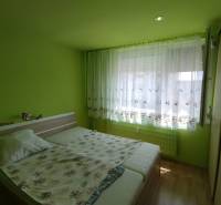 Green bedroom with a double bed and a large window in a three-room apartment.