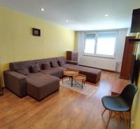 Living room in a 3-room apartment with a large brown sofa and wooden floors.
