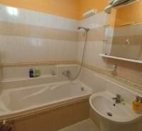 Bathroom with a bathtub and a sink in a 3-room apartment, tiles in shades of beige.