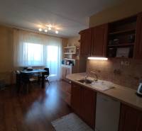 A kitchen in a 3-room apartment with a dining table and a wooden kitchen unit.