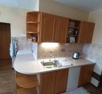 A kitchen in a 3-room apartment with a wooden cabinet, a sink, and a coffee maker.