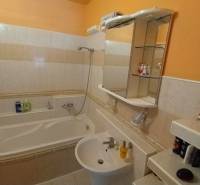 A bathroom in a 3-room apartment with a bathtub, a sink, and a mirrored cabinet.