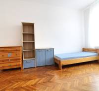 A room in a 3-room apartment with an oak floor, a bed, a wardrobe, and a shelf.