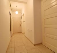 A narrow hallway with ceramic tiles and white doors in a 3-room apartment.