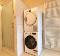 Bathroom with a washing machine, dryer, shower corner, and ladder radiator in a 3-room apartment.