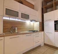 A kitchen in a 3-room apartment with white cabinets and wooden details on the walls.