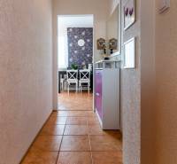 A hallway with a ceramic floor leading to the dining room in a 3-room apartment, with decorative wallpaper.