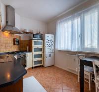 A kitchen in a 3-room apartment with a combination stove, refrigerator, and dining table.
