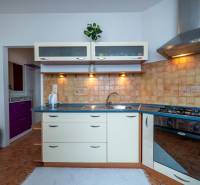 A kitchen in a 3-room apartment with a cooktop, sink, and storage cabinets.
