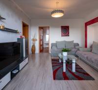 Living room in a 3-room apartment with a gray sofa, glass table, and television.