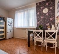 A kitchen in a 3-room apartment with a dining table, a plant, a refrigerator, and a microwave.