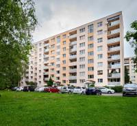An apartment building on Prostějovská Street in Prešov, surrounded by greenery and parked cars.