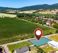 Aerial view of residential plots in Nižná Kamenica, surrounded by greenery and the village.