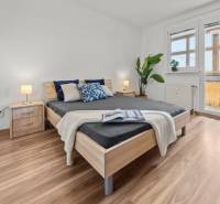 Bedroom with a large bed, nightstand, plant, and a view of the balcony, 3-room apartment.