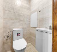 A toilet with ceramic tiles and a sink in a 3-room apartment.