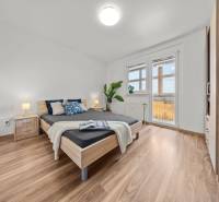 Bedroom in a 3-room apartment with a wooden bed and a balcony.
