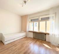 A bright room in a 2-room apartment with simple furniture and a large window.