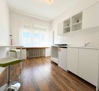A bright kitchen in a 2-room apartment with laminate flooring and white cabinets.