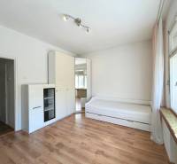 A bright room space in a 2-room apartment with a bed, a cabinet, and a large window.