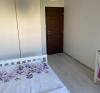A bedroom in a 3-room apartment with a bed, a built-in wardrobe, and wooden doors.