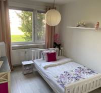A simple bedroom with a bed, a window, and a shelf in a 3-room apartment.