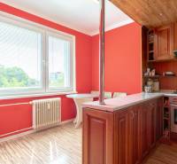 A kitchen with a wooden cabinet, dining table, window, and red walls in a studio apartment.