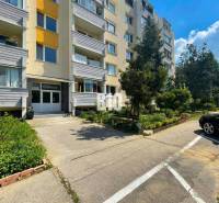 Entrance of an apartment building with parking and greenery in Nitra, suitable for a 1-bedroom apartment.