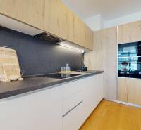 A kitchen in a 2-room apartment with wooden furniture and a black countertop.